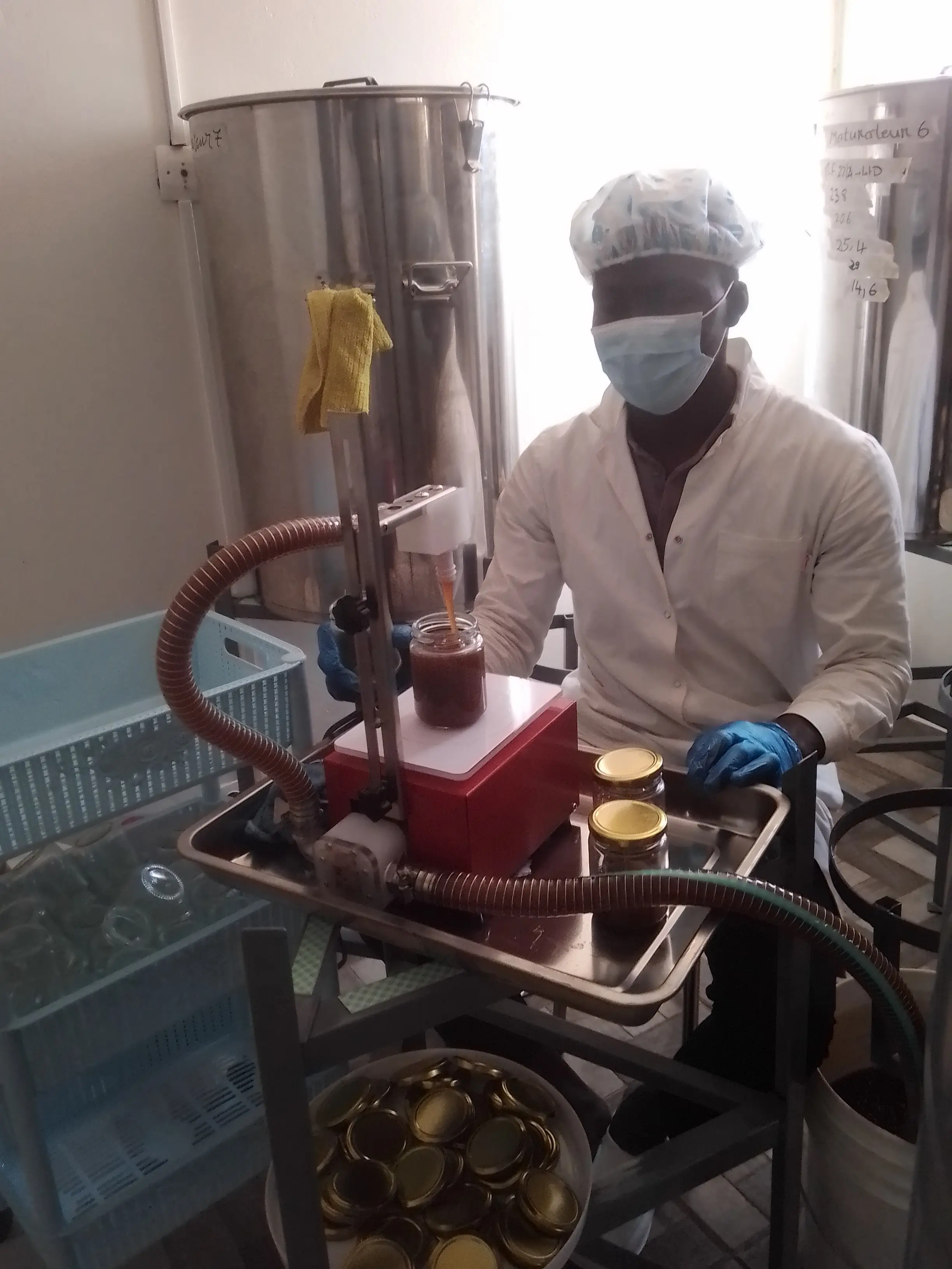 Mise en pot du miel à l'atelier, remplissage au doseur depuis le maturateur